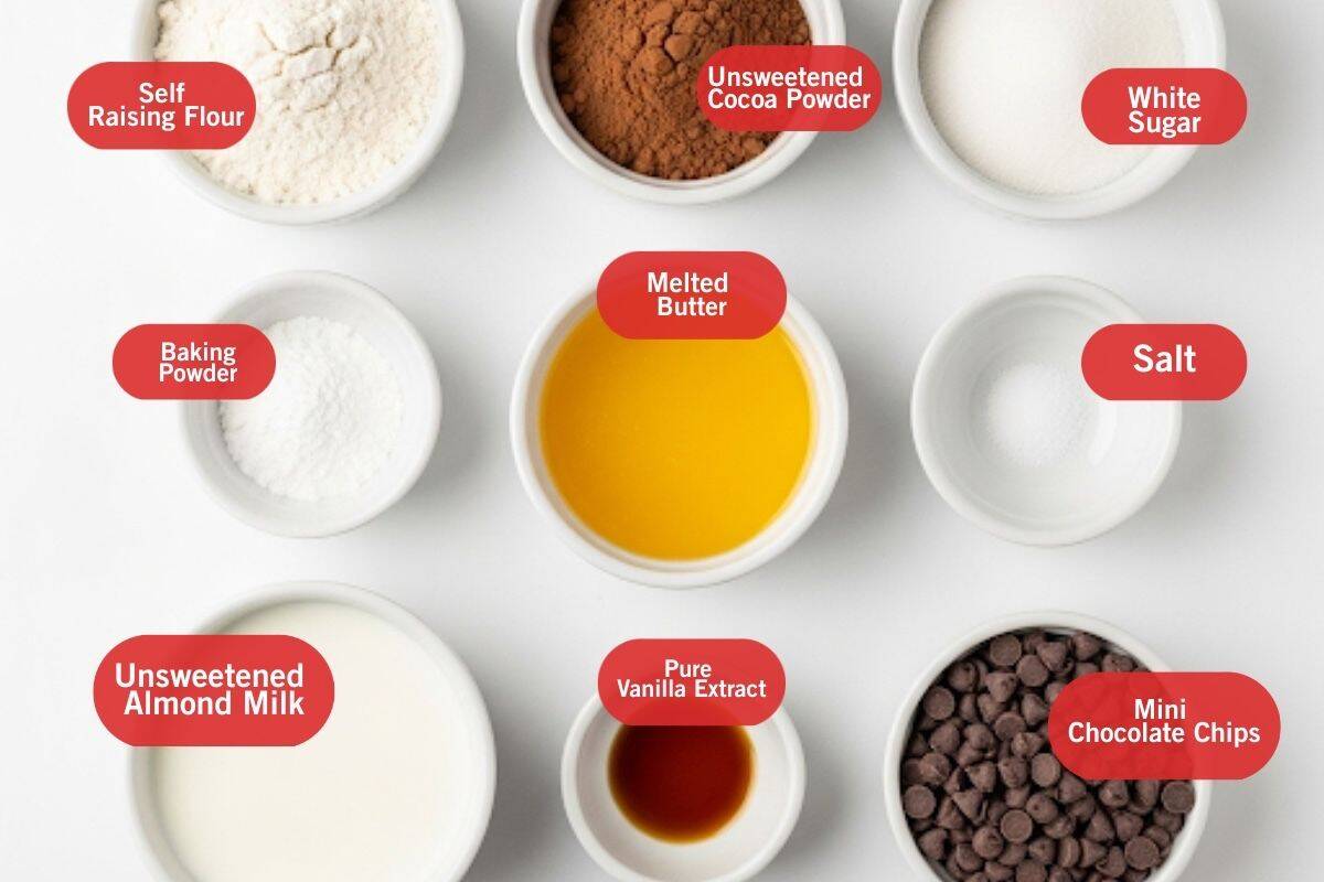 Flat lay photo of ingredient shot of self raising flour, unsweetened cocoa powder, white sugar, baking powder, melted butter, salt, unsweetened almond milk, pure vanilla extract, mini chocolate chips