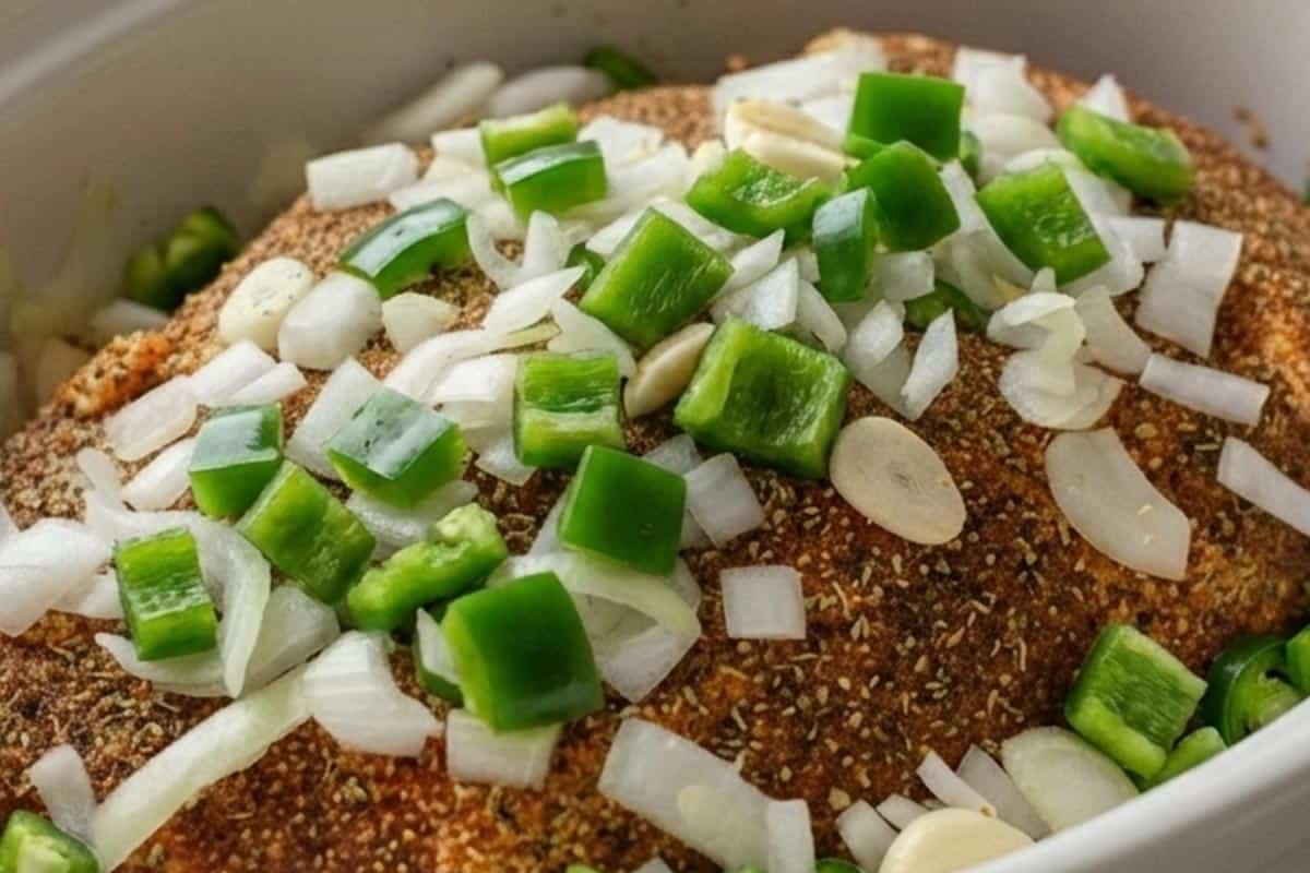 Scattered the chopped onion, garlic, and jalapeño over the pork.