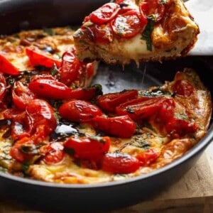 Garlic infused, Caprese Frittata with pan fried, juicy tomato and fresh basil flavors in a pan.