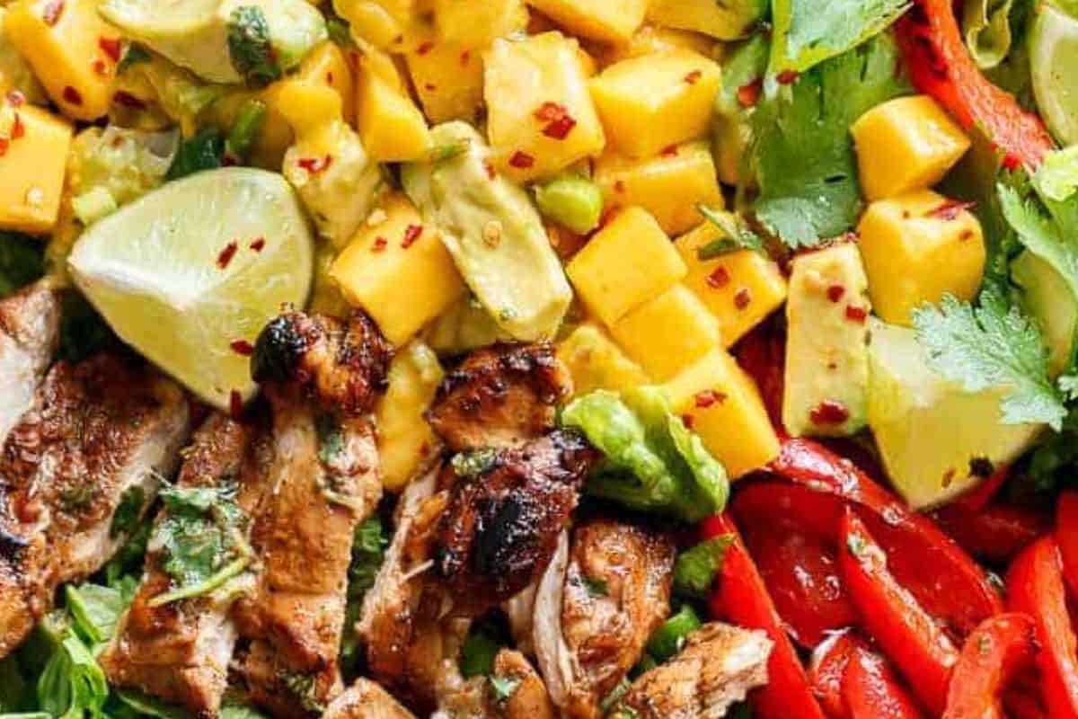 Toss lettuce, peppers, mango, avocado, and green onion together. Slice chicken and place on top, drizzle with the reserved dressing, and garnish.