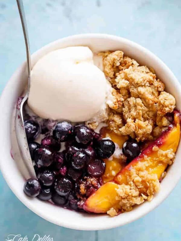 Mango Blueberry Crumble with fresh berries and ice cream scoops in a bowl
