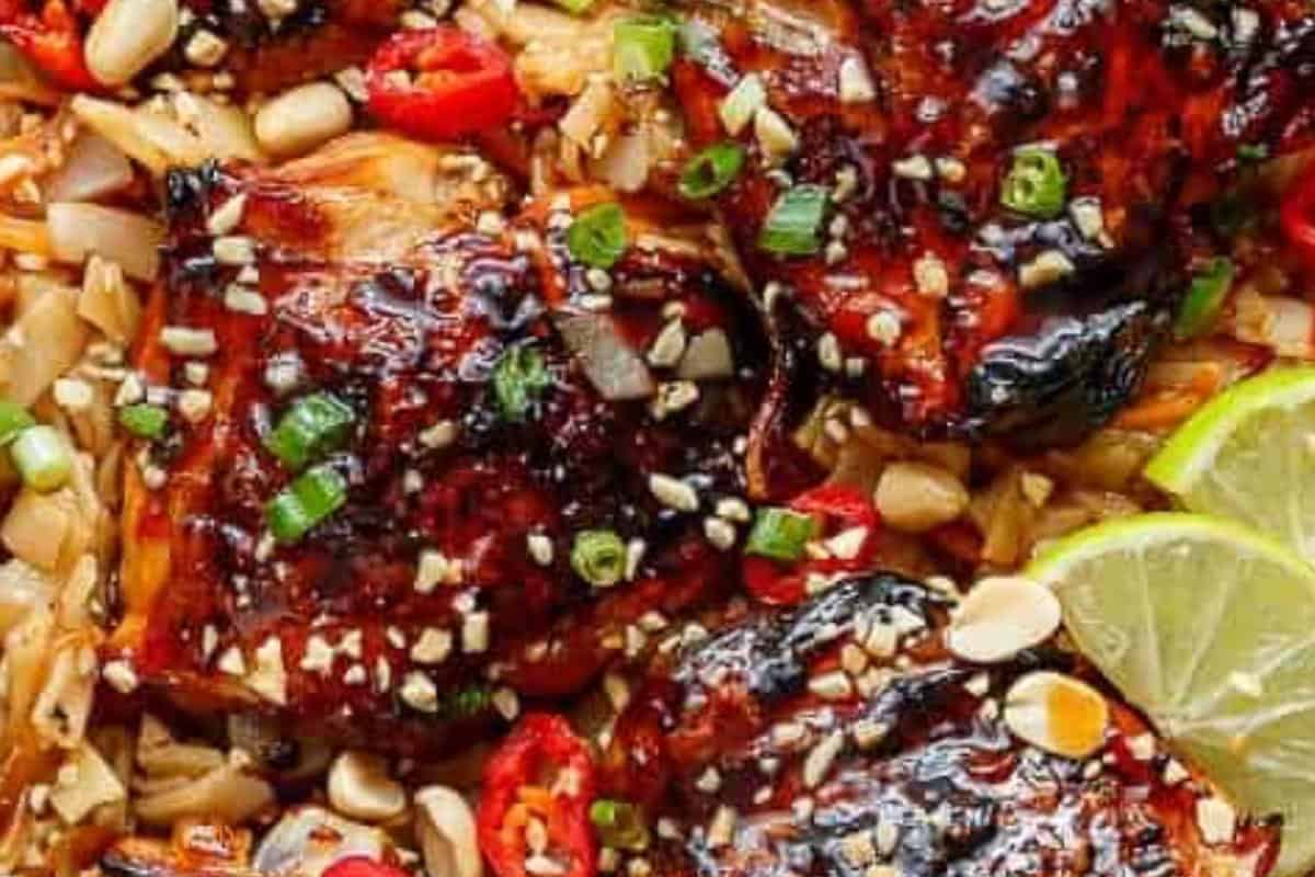 Return the chicken to the skillet over the noodles, allowing everything to come together. Garnish with green onions, red chilli, and crushed peanuts