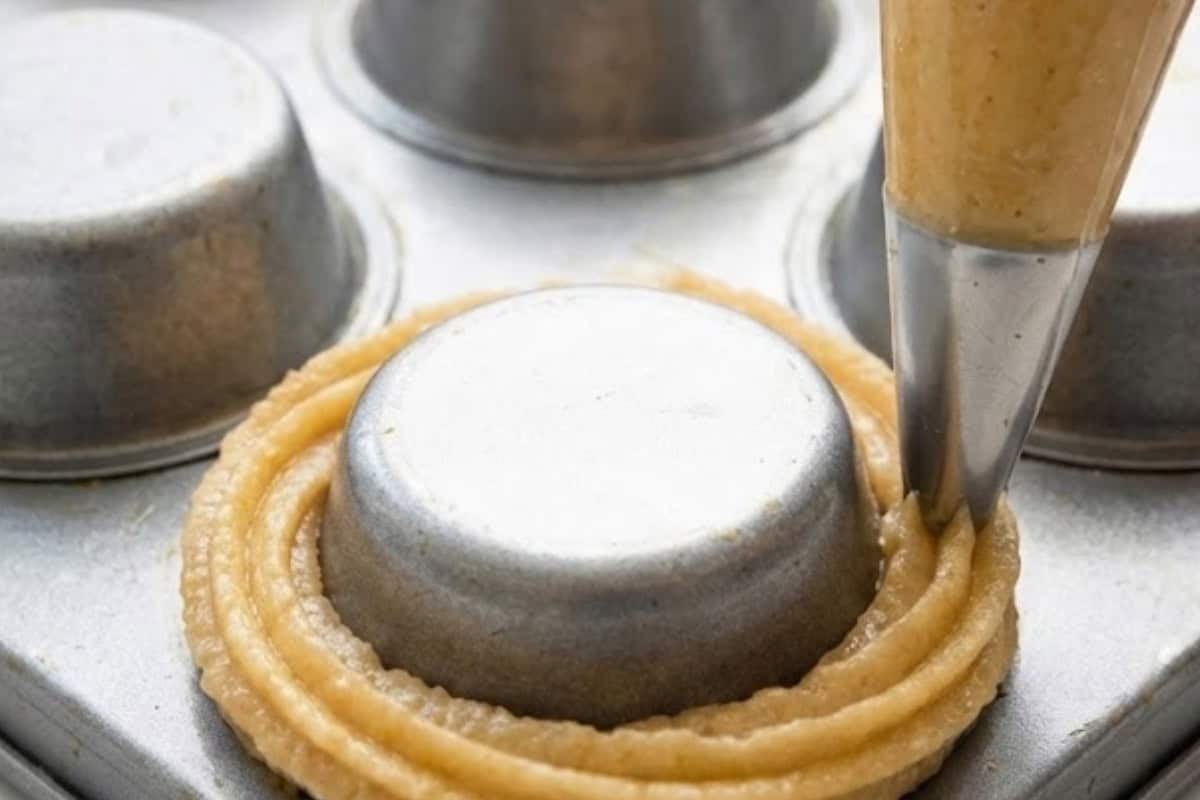 Transfer the dough to a piping bag with a large star tip and pipe circles around every second muffin cup