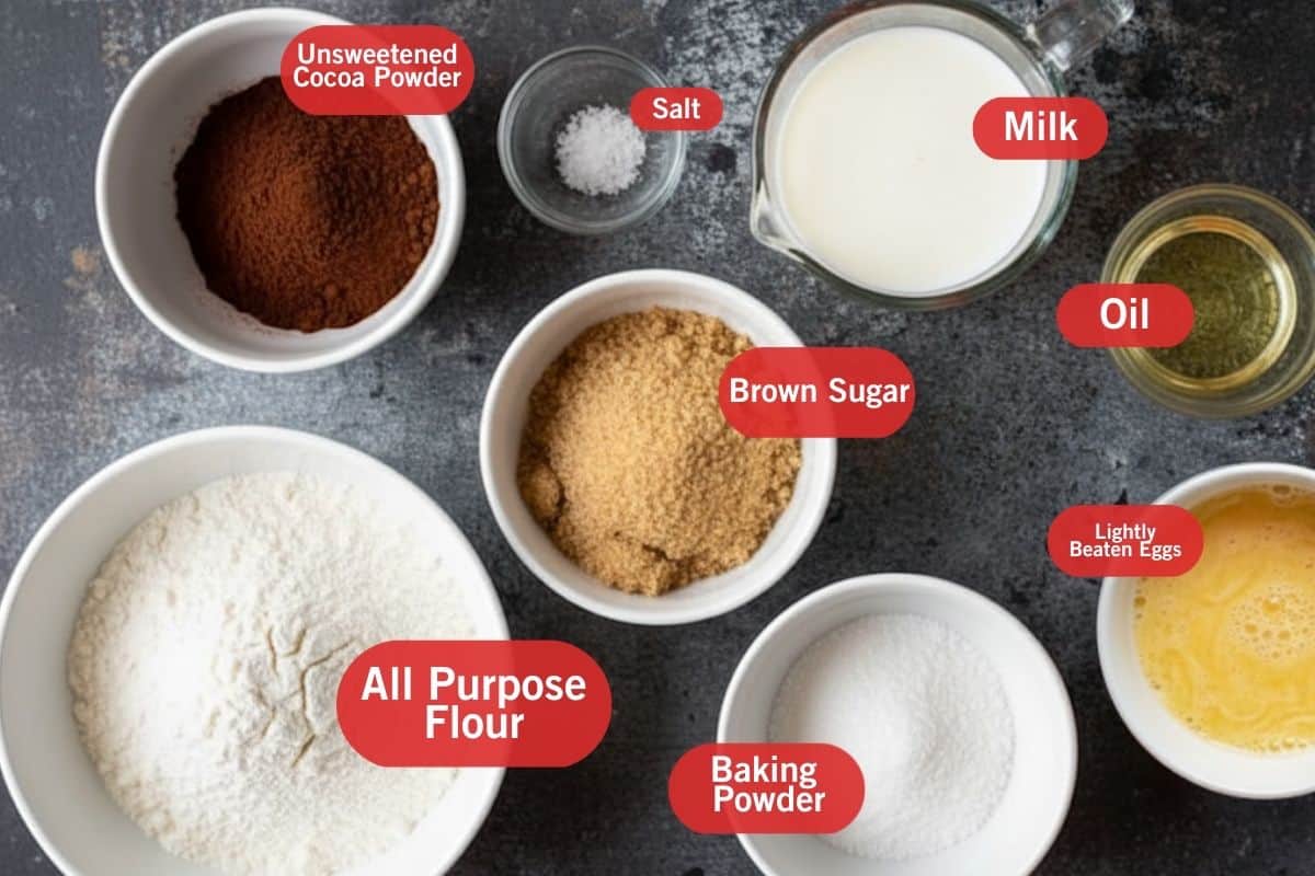 Flat lay photo of ingredient shot, all purpose flour, unsweetened cocoa powder, brown sugar, baking powder, salt, lightly beaten eggs, oil, milk