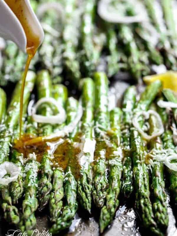 A dressing pouring over Garlic Browned Butter Baked Asparagus with Parmesan Cheese