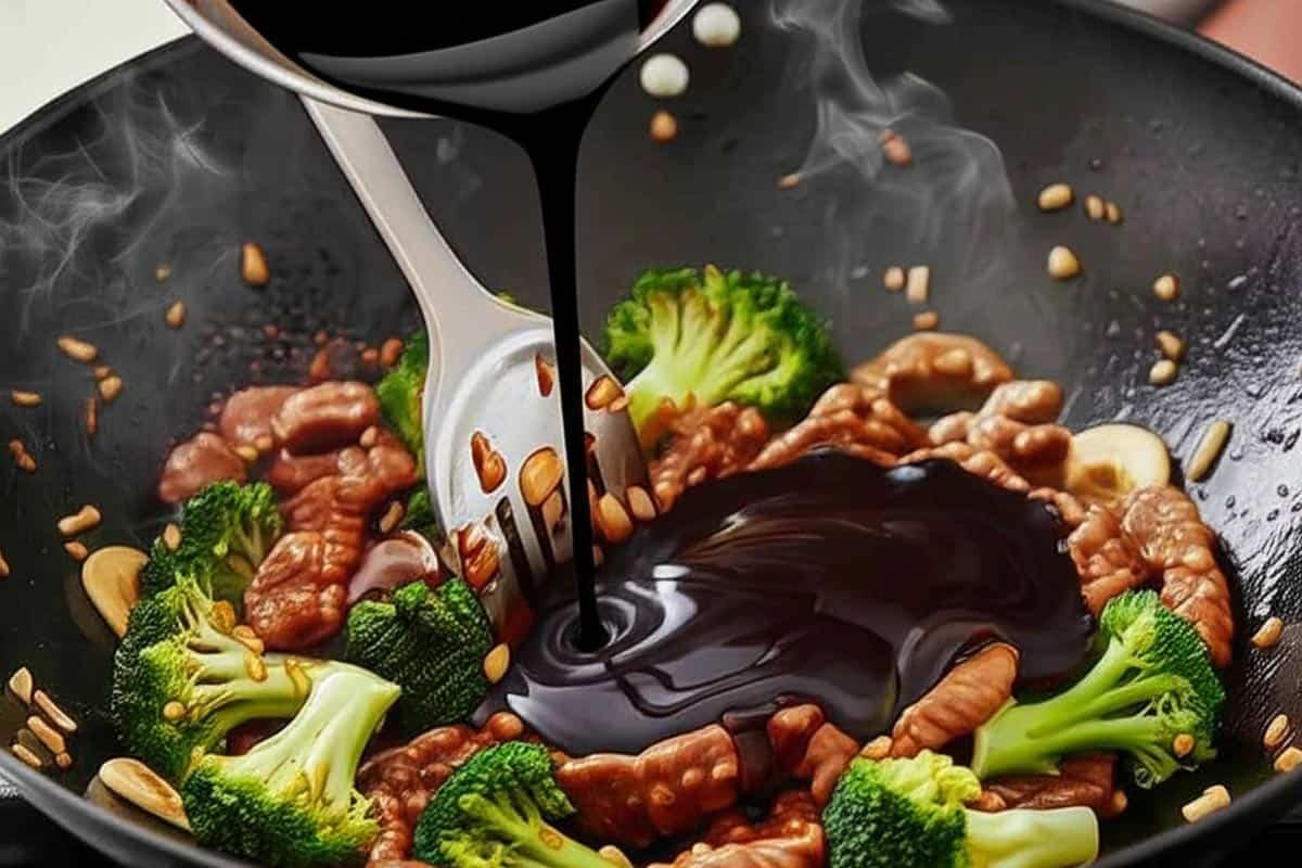Pouring in the prepared sauce to the broccoli and cooked beef.