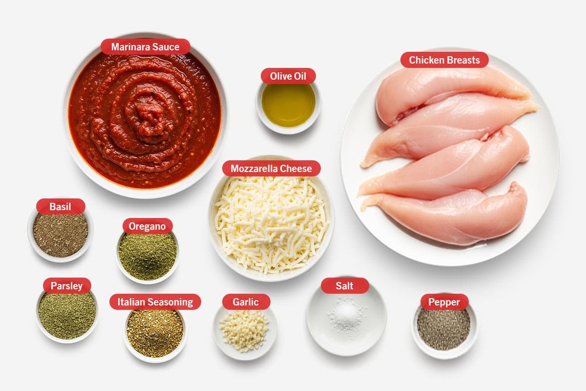 Top shot of ingredients: Marinara sauce, olive oil, chicken breasts, basil, oregano, mozzarella cheese, parsley, Italian seasoning, garlic, salt, pepper.