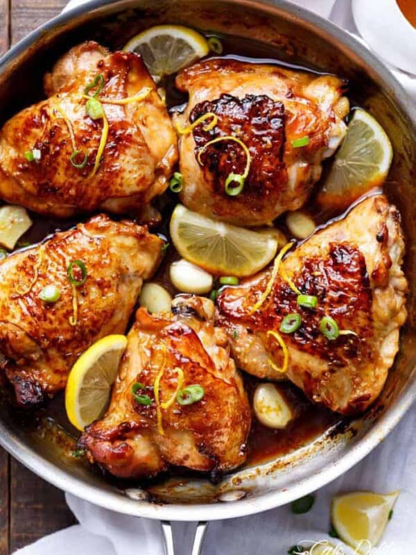 Honey Lemon Garlic Chicken pieces with lemon wedges in a pan