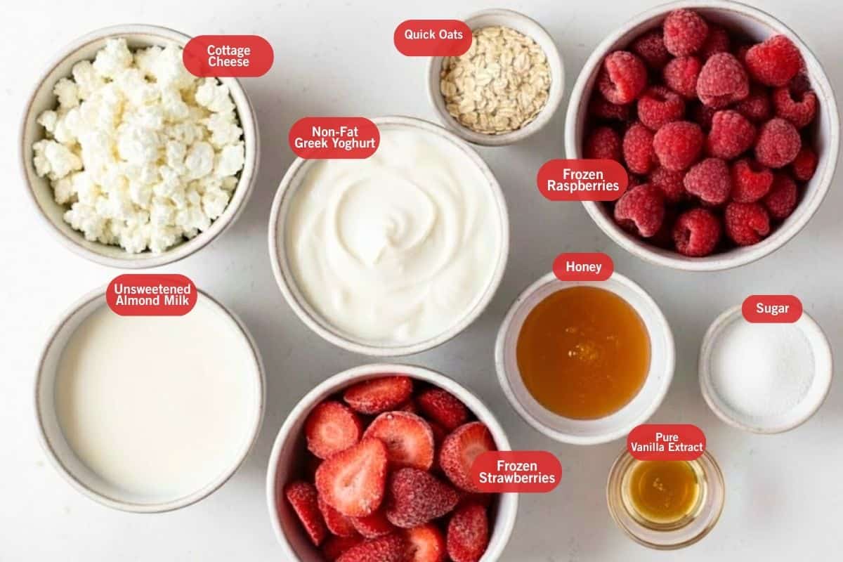 Flat lay photo of ingredient shot of cottage cheese, quick oats, frozen raspberries, sugar, honey, frozen strawberries, pure vanilla extract, unsweetened almond milk, non fat greek yoghurt