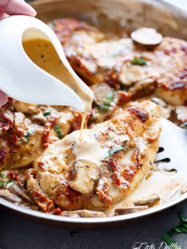 A creamy sauce pouring over grilled chicken piece