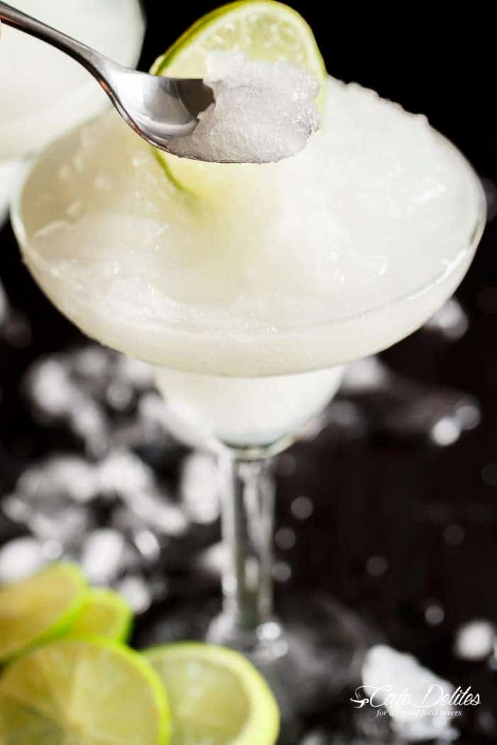 A silver spoon scooping frozen slushy out of a cocktail glass. 