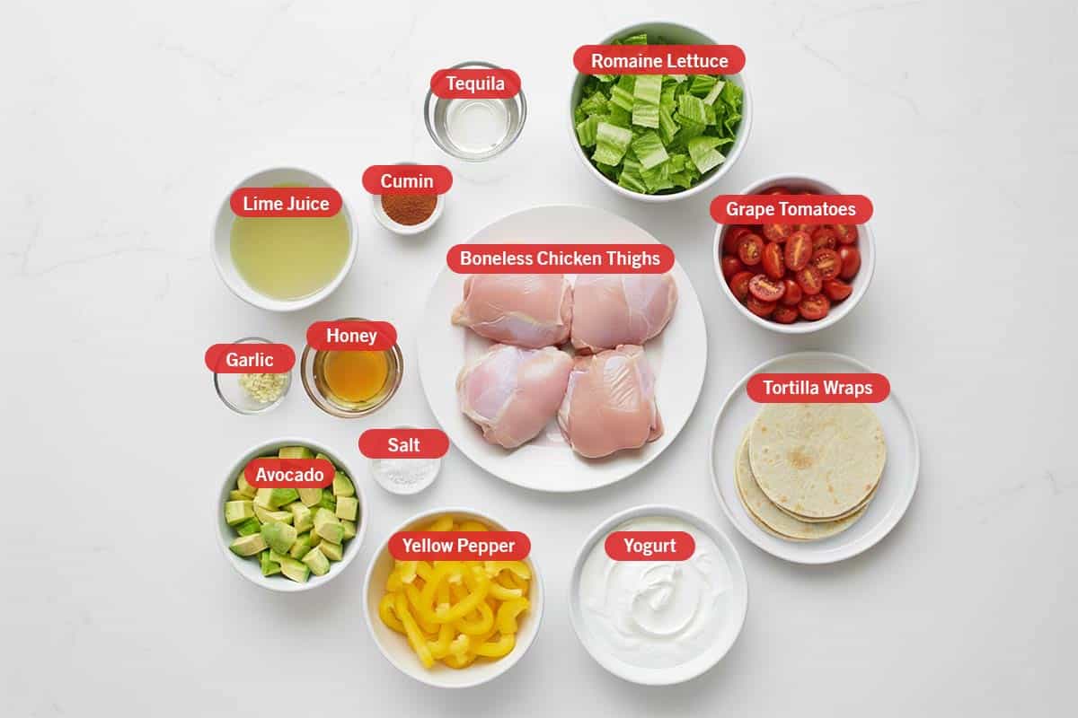 Top shot of ingredients: lime juice, cumin, tequila, Romaine lettuce, grape tomatoes, tortilla wraps, yogurt,yellow pepper, avocado, salt, garlic, honey, and boneless chicken thighs. - 2