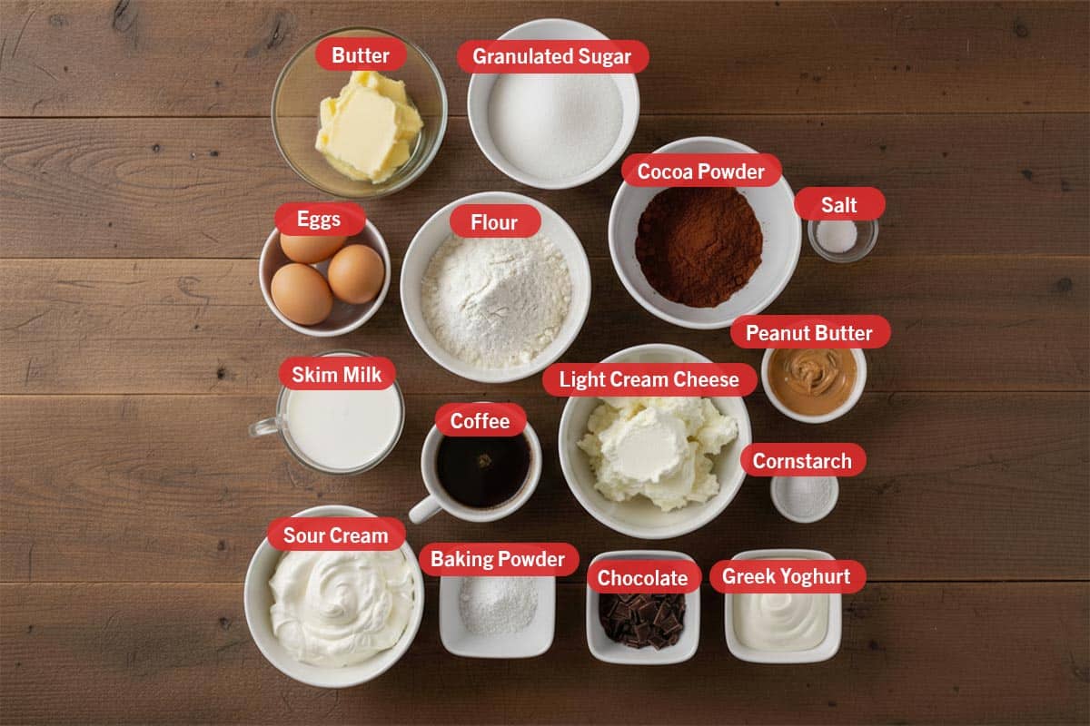 Top shot of ingredients: butter, granulated sugar, eggs, flour, cocoa powder, salt, skim milk, coffee, light cream cheese, peanut butter, cornstarch, sour cream, baking powder, chocolate, and greek yoghurt. - 2