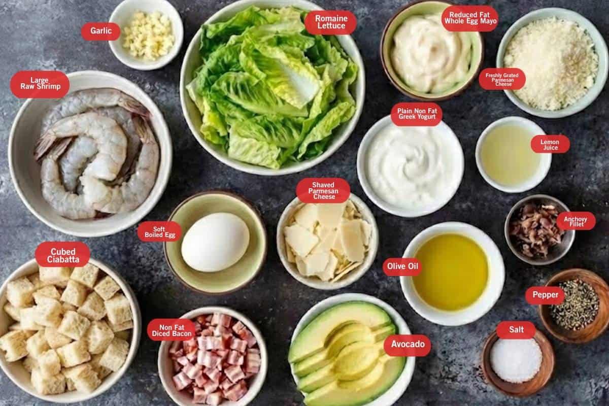 Flat lay photo of cubed ciabatta, large raw shrimp, lemon juice, garlic, salt, pepper, non fat diced bacon, soft boiled egg, romaine lettuce, avocado, shaved  parmesan cheese, non far greek yogurt,  reduced fat whole egg mayo, olive oil, freshly grated parmesan cheese - 2