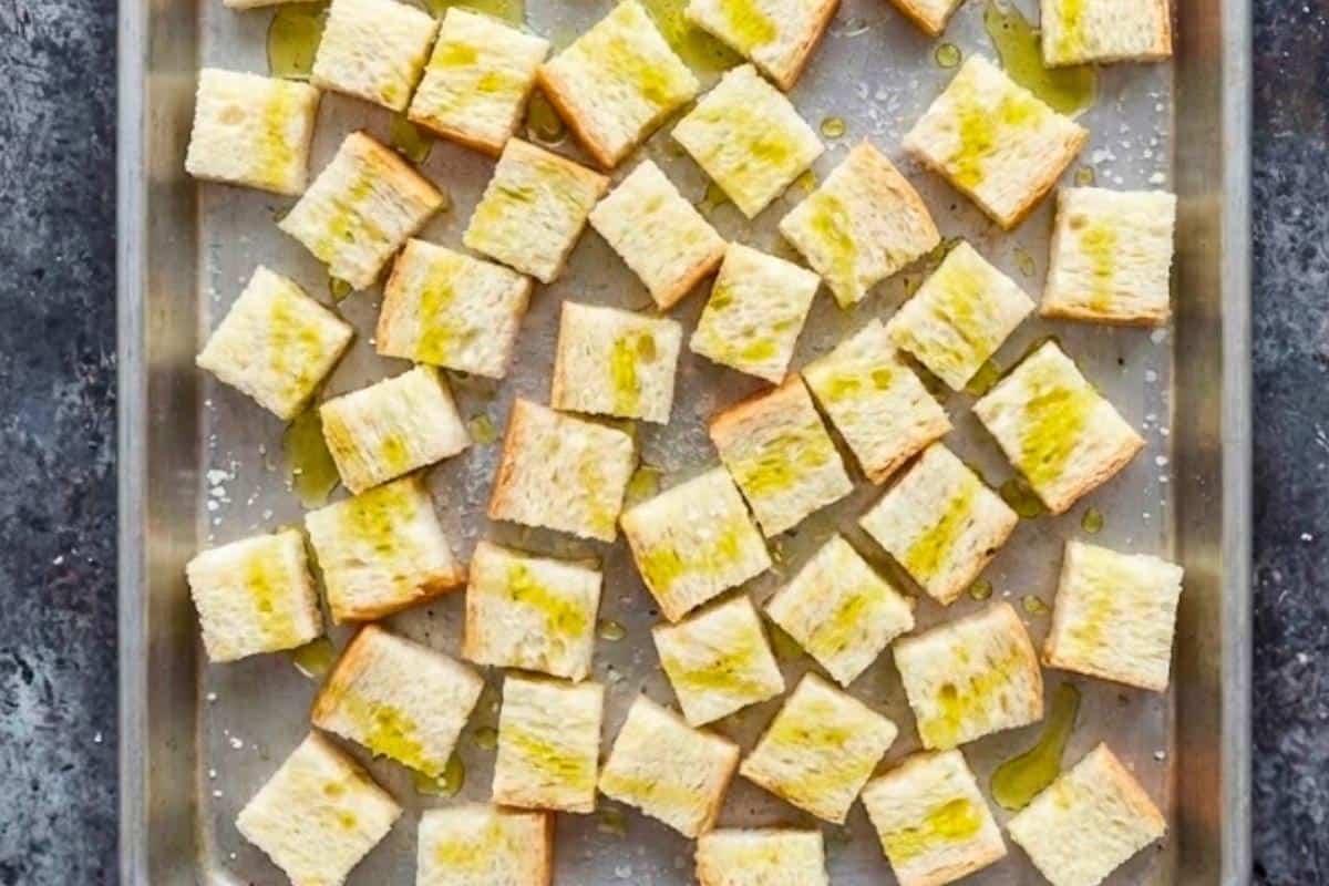 Spread cubed bread on a baking tray, drizzle or spray with olive oil, and grill on the middle rack until golden and crisp. - 3