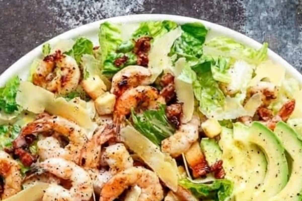 Place the washed and dried romaine lettuce into a large salad bowl. Add the warm shrimp, crispy bacon, avocado slices, shaved Parmesan, and toasted croutons. - 8