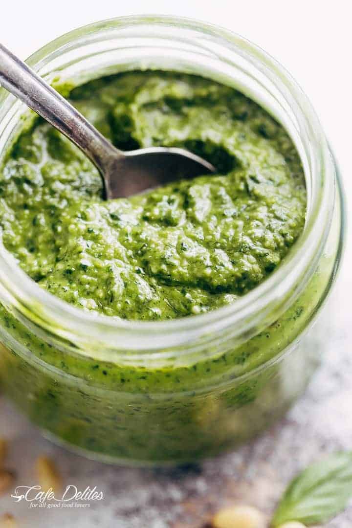 Basil pesto in a jar with a spoon.