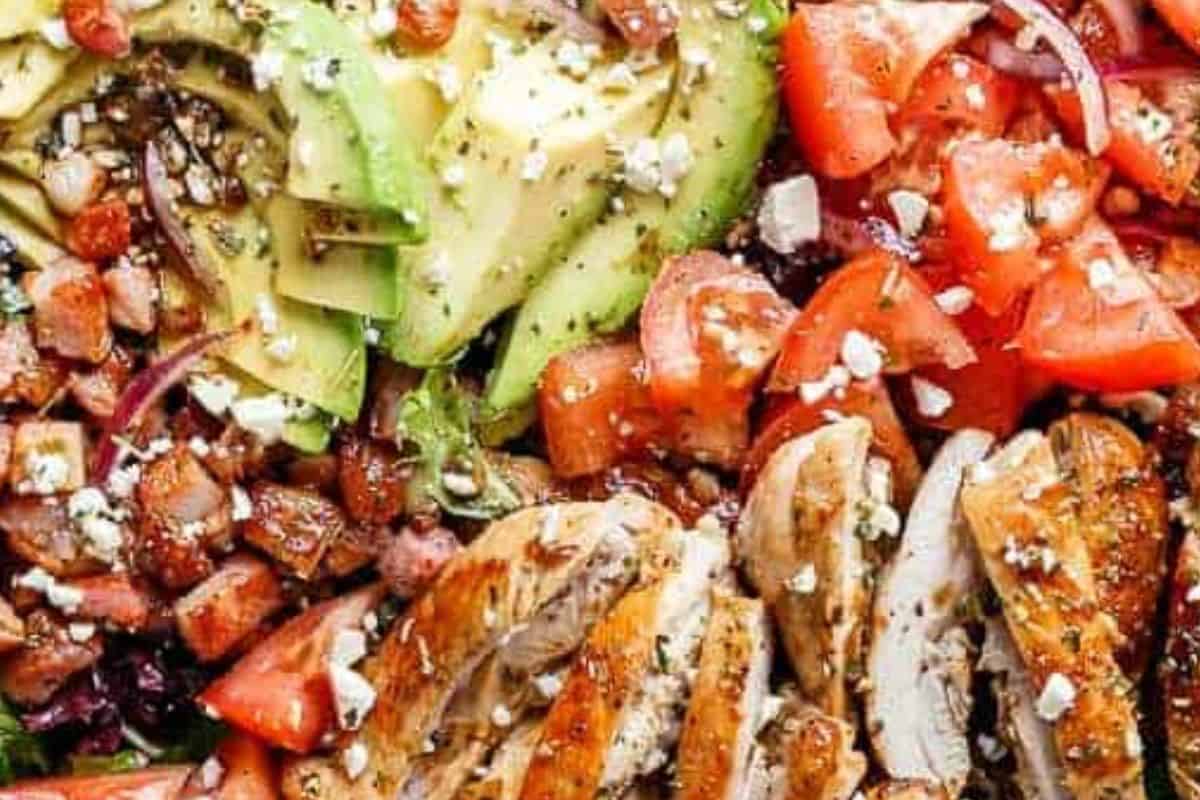 Arrange the lettuce, tomatoes, onion, and avocado in a bowl. Add the chicken and bacon, sprinkle with feta and extra Italian seasoning, and drizzle with the remaining dressing.