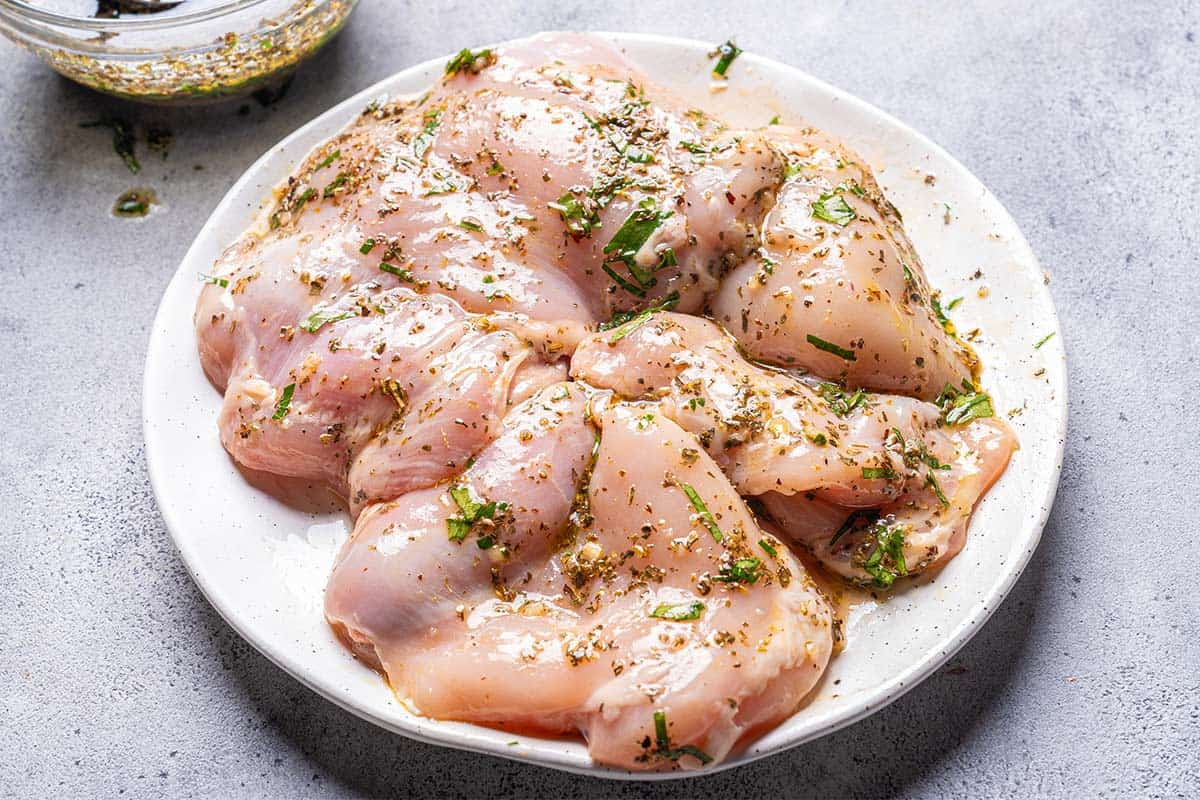 chicken on a white plate marinated in salad dressing