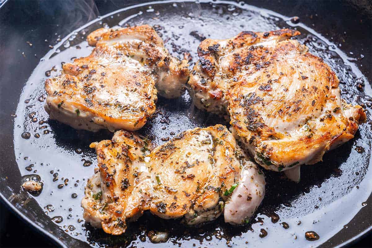 marinated chicken being seared in a skillet