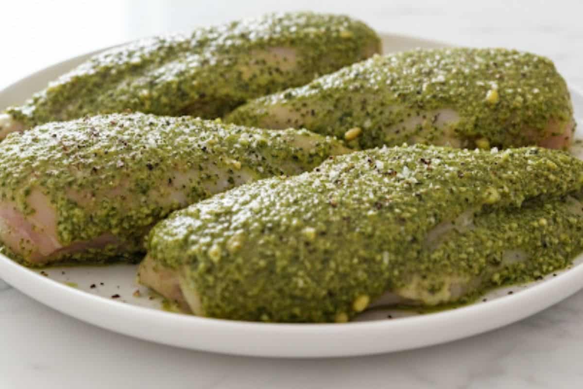 Smother the chicken breast fillets with pesto and season with salt and pepper.