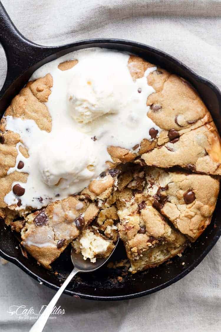 A crispy, soft Cheesecake Stuffed Chocolate Chip Skillet Cookie cut into pieces with some ice cream scoops