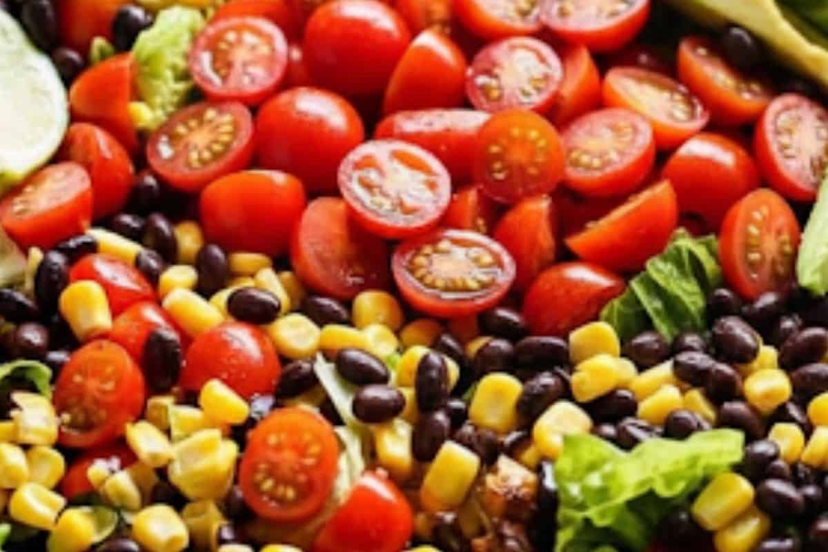 Arrange romaine lettuce, halved tomatoes, avocado slices, black beans, and corn in a large serving bowl.