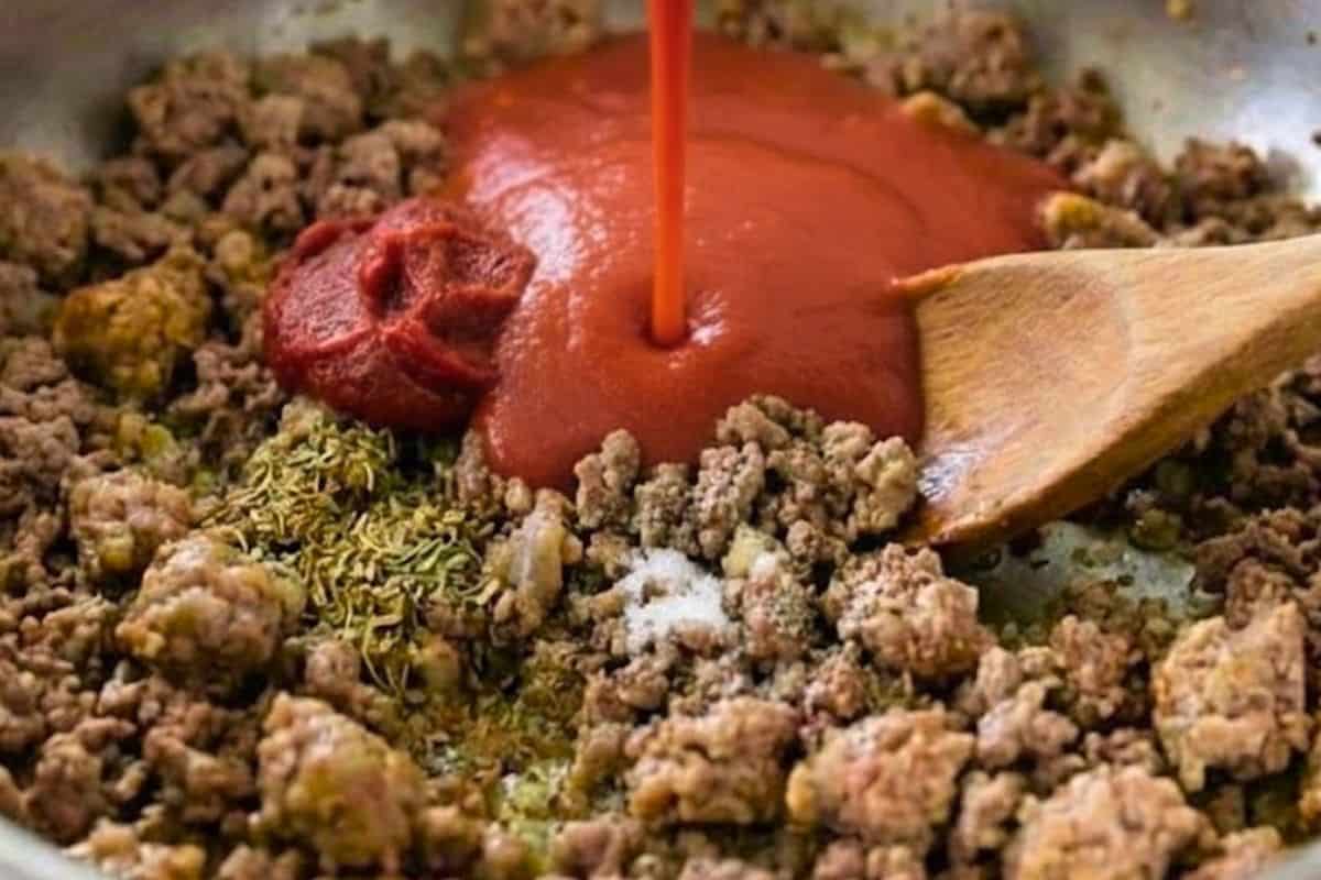 Stir in three quarters of the tomato puree, tomato paste, bouillon, salt, pepper, oregano, and basil - 6