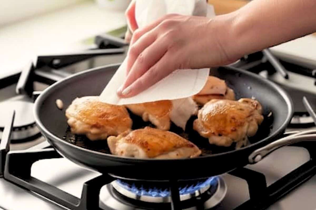 Blot the chicken thighs with paper towel and keep the pan on the heat.