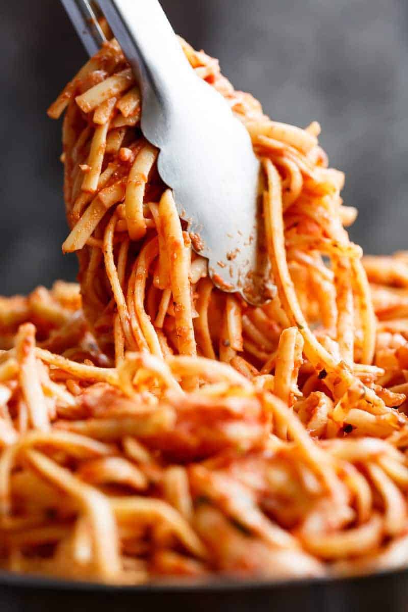 tongs holding up 15-Minute Creamy Tomato Garlic Butter Shrimp