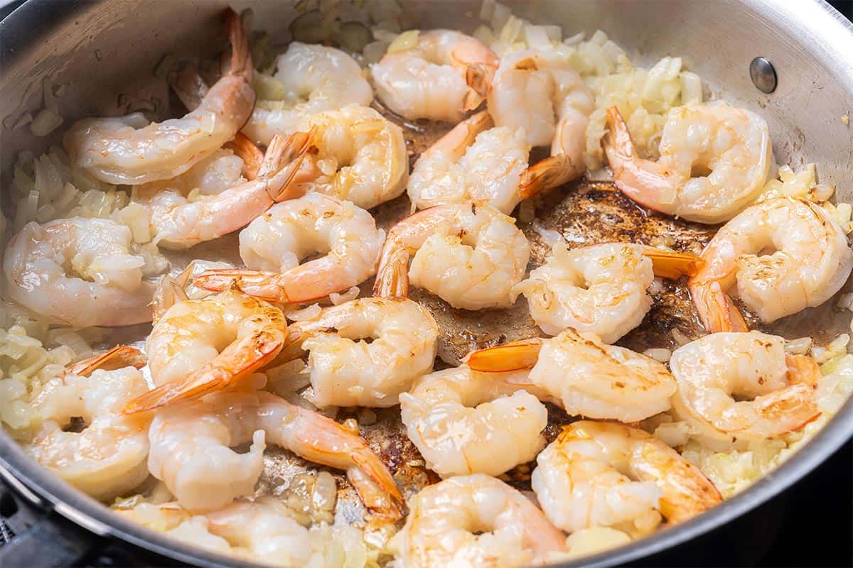 butter onion, garlic and shrimp in a skillet being fried