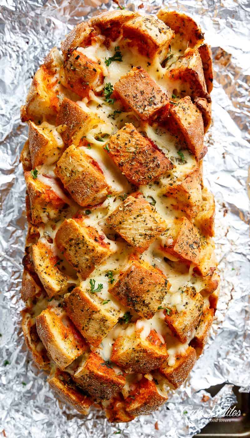 This Garlic Butter Pizza Pull Apart Bread is smothered in garlic butter, stuffed with pizza fillings, and topped with so.much.cheese! | https://cafedelites.com