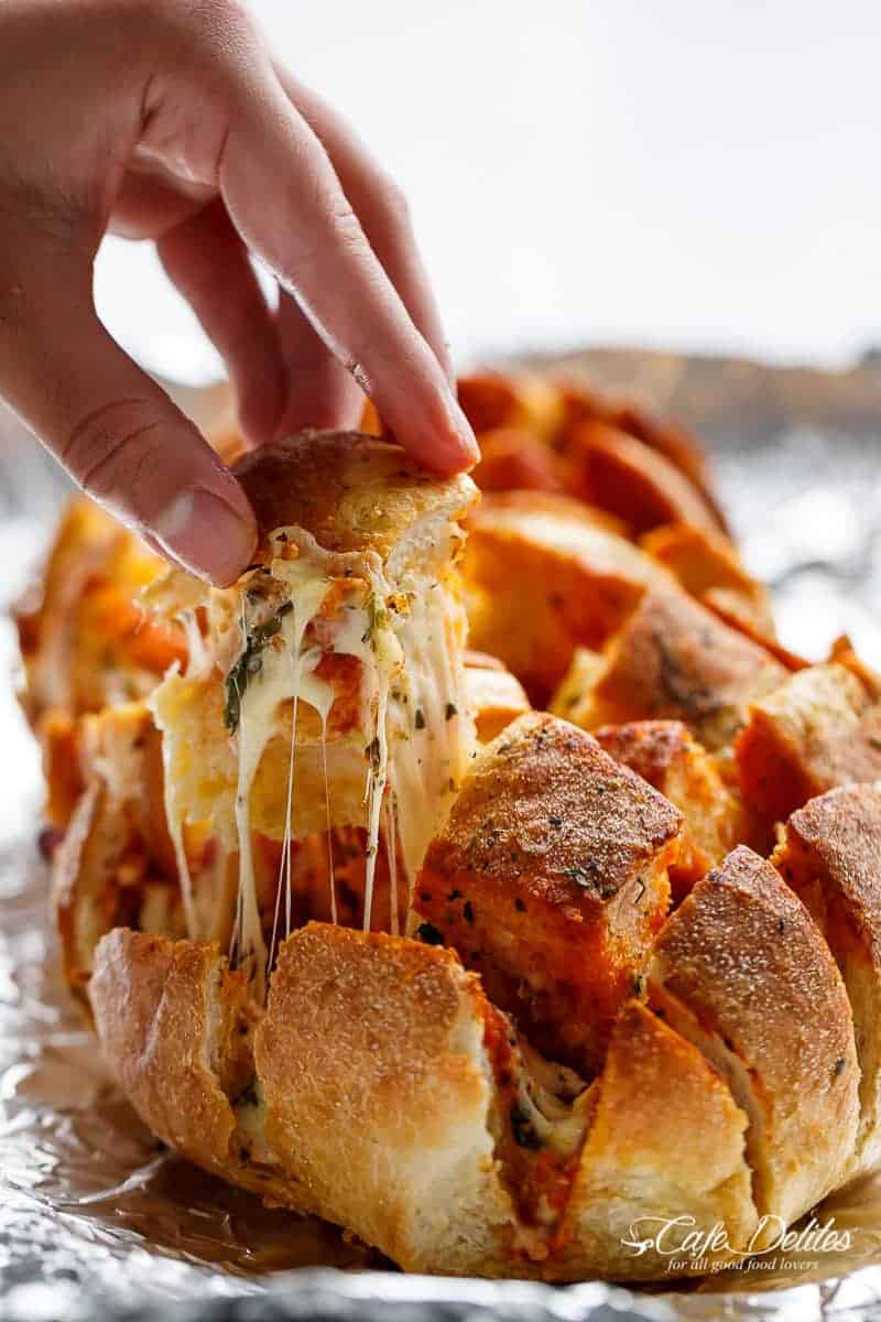 This Garlic Butter Pizza Pull Apart Bread is smothered in garlic butter, stuffed with pizza fillings, and topped with so.much.cheese! | https://cafedelites.com