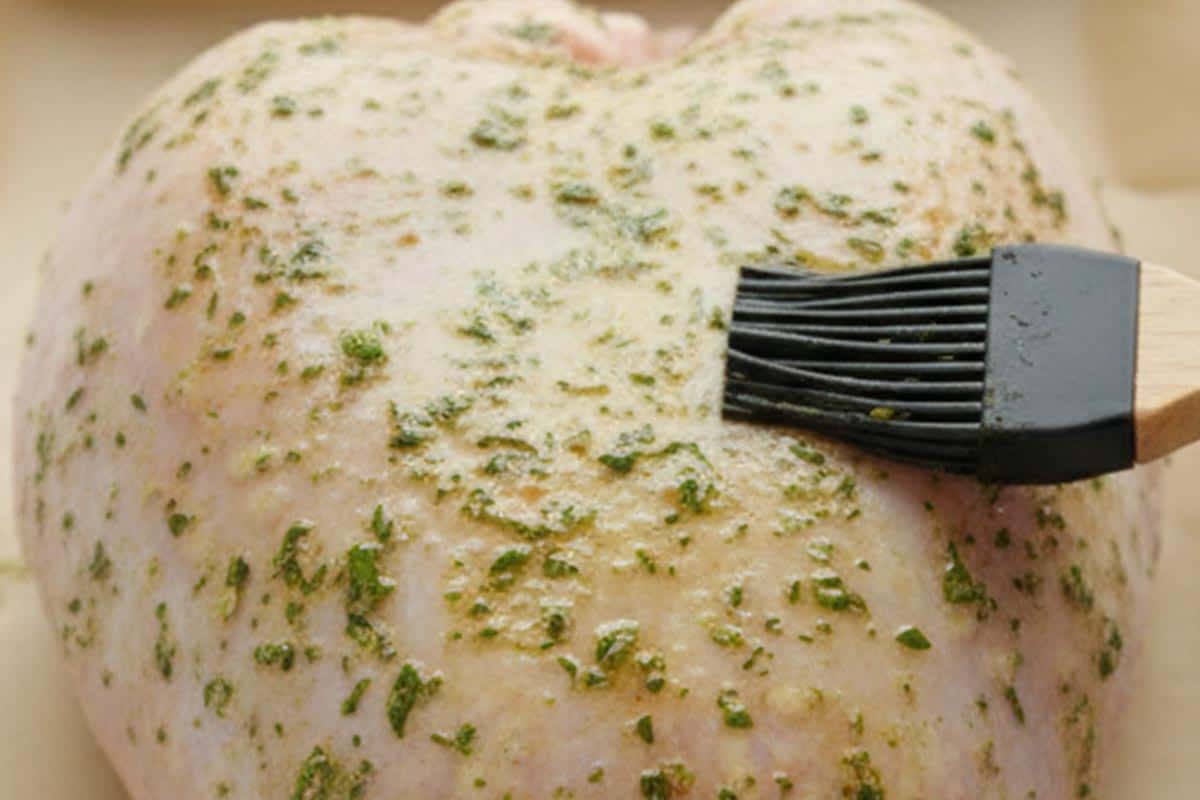 Brushing the turkey with the herb mixture.