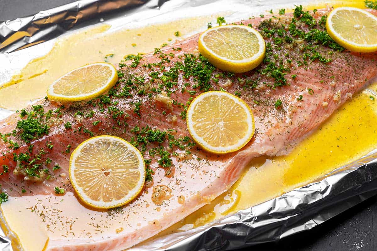 salmon arranged on a tray with lemon and garlic butter, uncooked