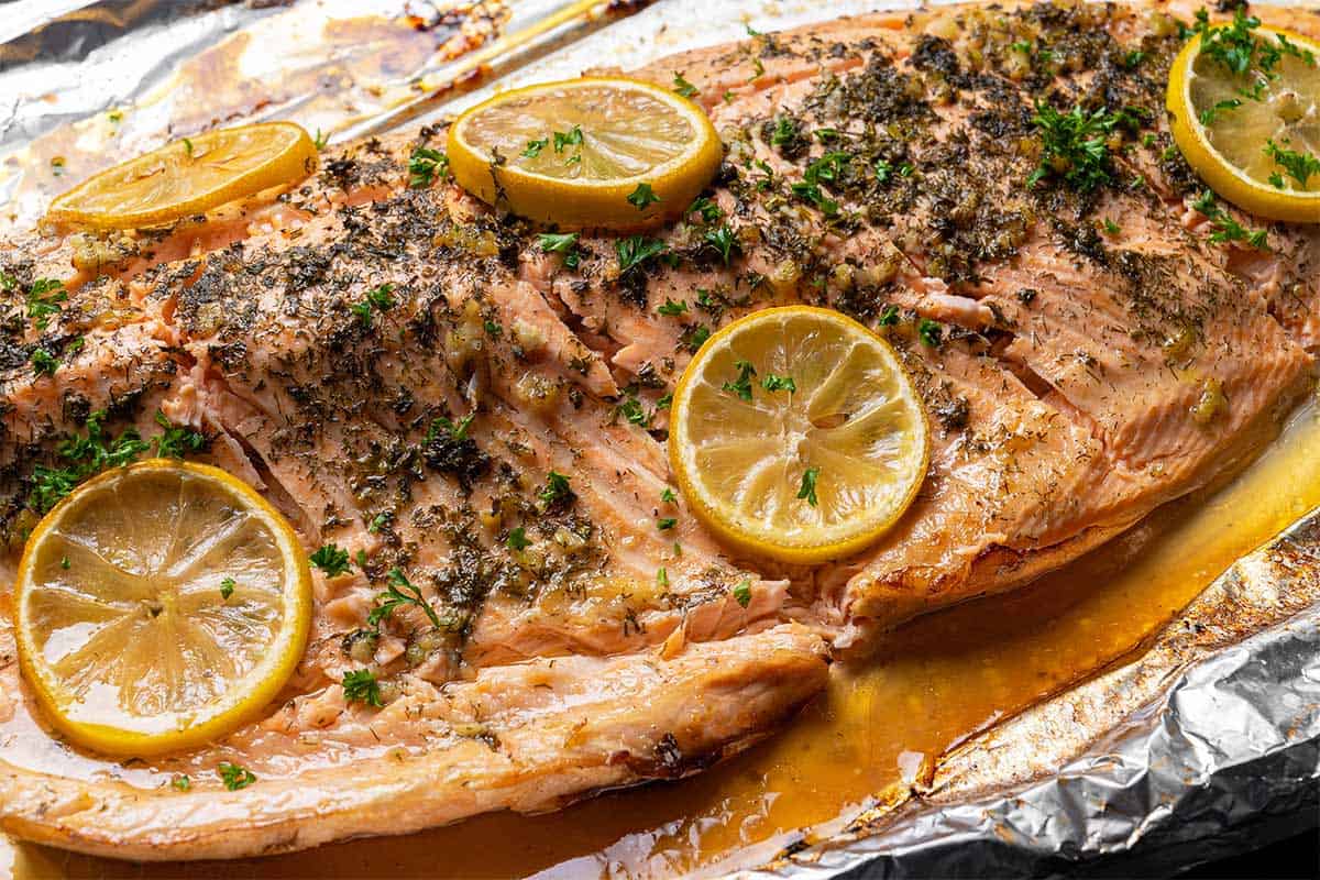 salmon arranged on a tray with lemon and garlic butter, cooked