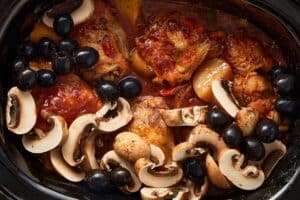 Mushrooms and black olives added to chicken cacciatore in the slow cooker