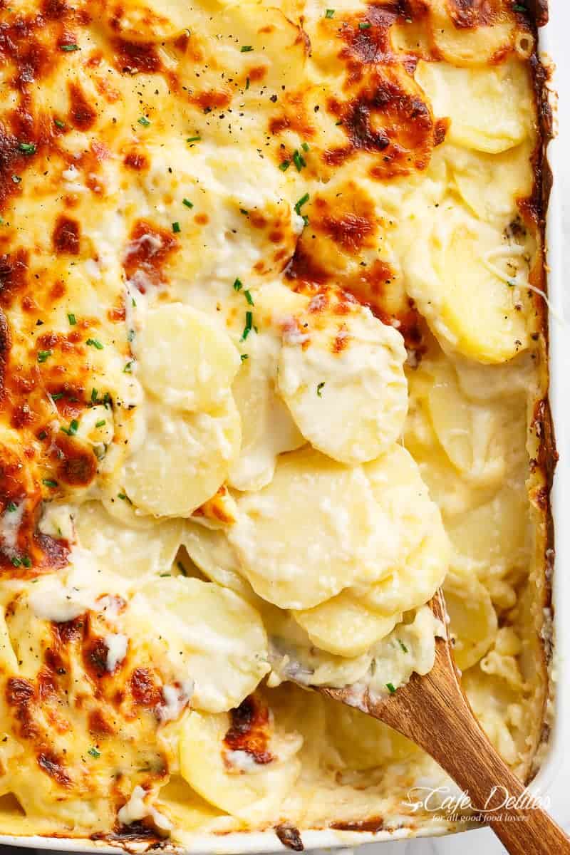 Garlic Parmesan Scalloped Potatoes layered in a creamy garlic sauce with parmesan and mozzarella is the best side dish to any meal! | https://cafedelites.com