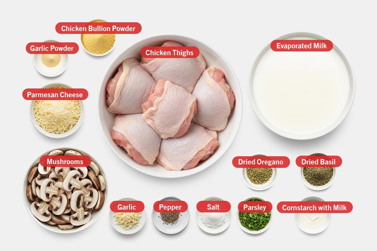 Top shot of ingredients: Chicken bullion powder, chicken thighs, evaporated milk, parmesan cheese, mushrooms, garlic, pepper, salt, parsley, garlic powder, dried oregano, dried basil, and cornstarch with milk.
