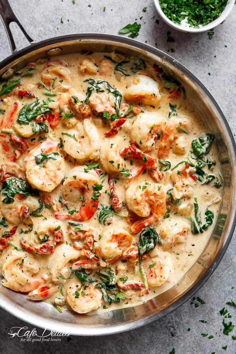 Creamy Garlic Butter Tuscan Shrimp coated in a light and creamy sauce filled with garlic, sun dried tomatoes and spinach! Packed with incredible flavours! | https://cafedelites.com