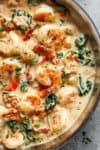 Creamy Garlic Butter Tuscan Shrimp coated in a light and creamy sauce filled with garlic, sun dried tomatoes and spinach! Packed with incredible flavours! | https://cafedelites.com