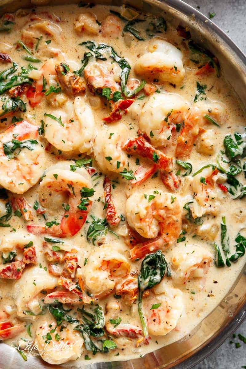 Creamy Garlic Butter Tuscan Shrimp coated in a light and creamy sauce filled with garlic, sun dried tomatoes and spinach! Packed with incredible flavours! | https://cafedelites.com