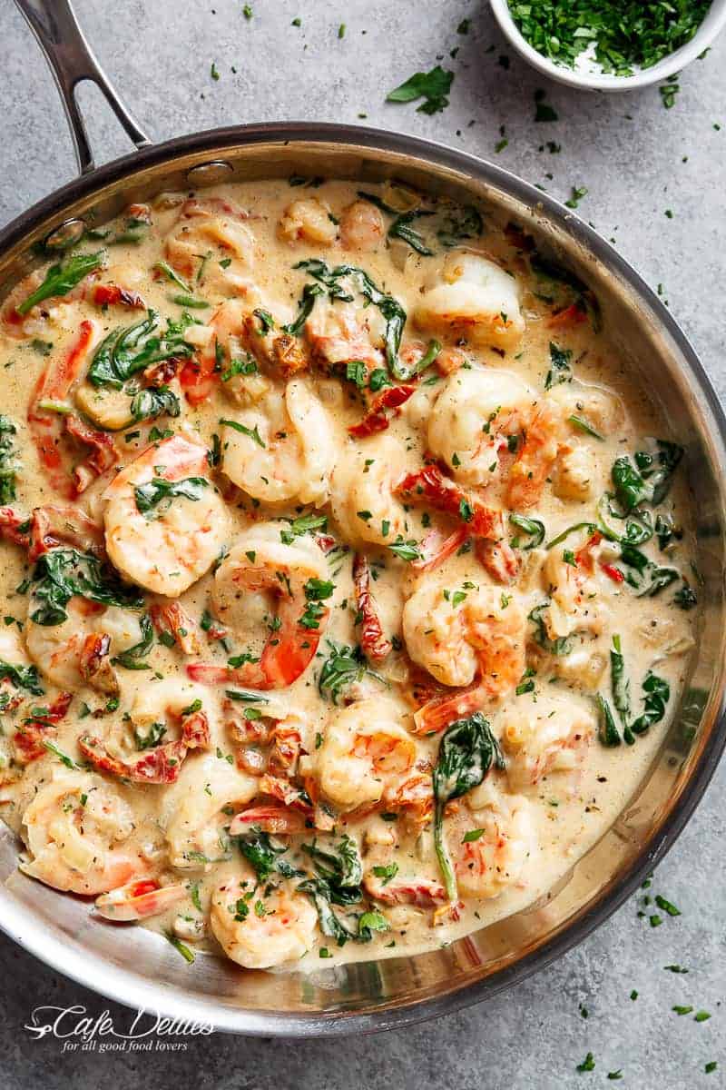 Creamy Garlic Butter Tuscan Shrimp coated in a light and creamy sauce filled with garlic, sun dried tomatoes and spinach! Packed with incredible flavours! | https://cafedelites.com