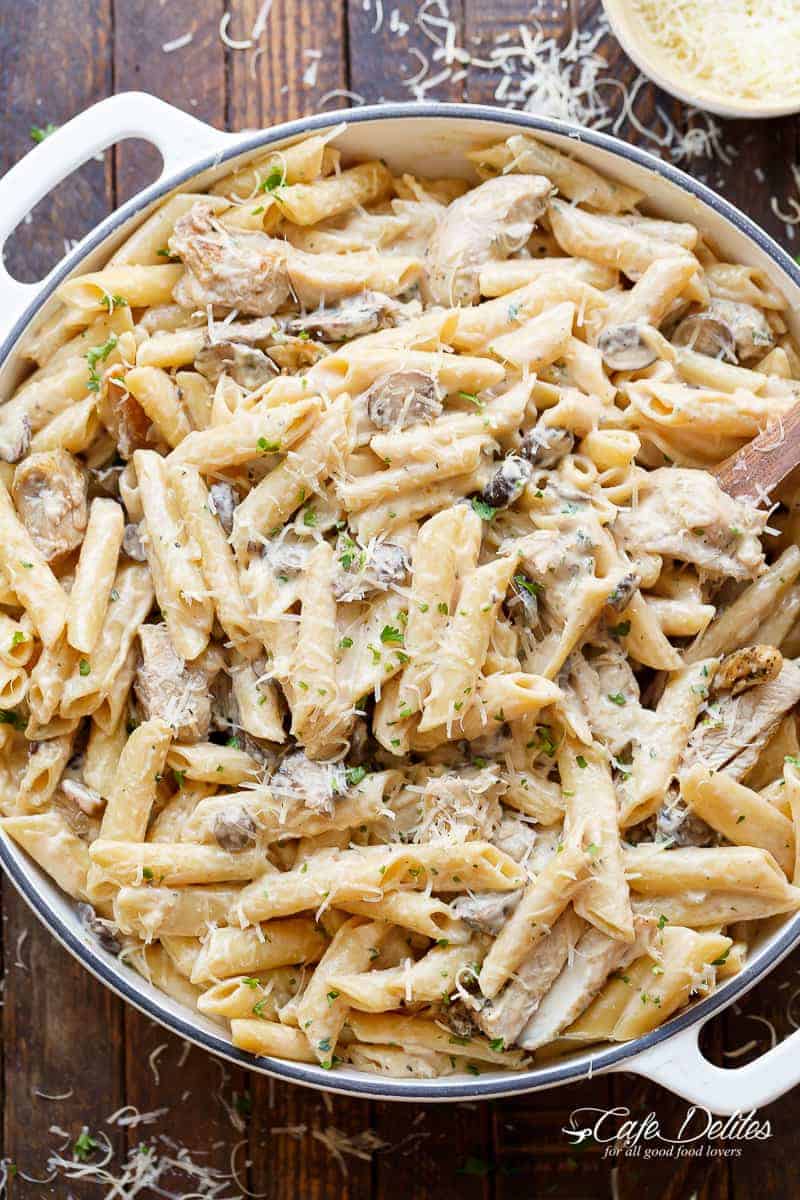 Seared chicken strips are mixed through this One-Pot Creamy Mushroom Chicken Pasta, with garlic, mushrooms and parmesan cheese in a large le creuset pot. The pasta is sprinkled with freshly grated parmesan and fresh herbs. 