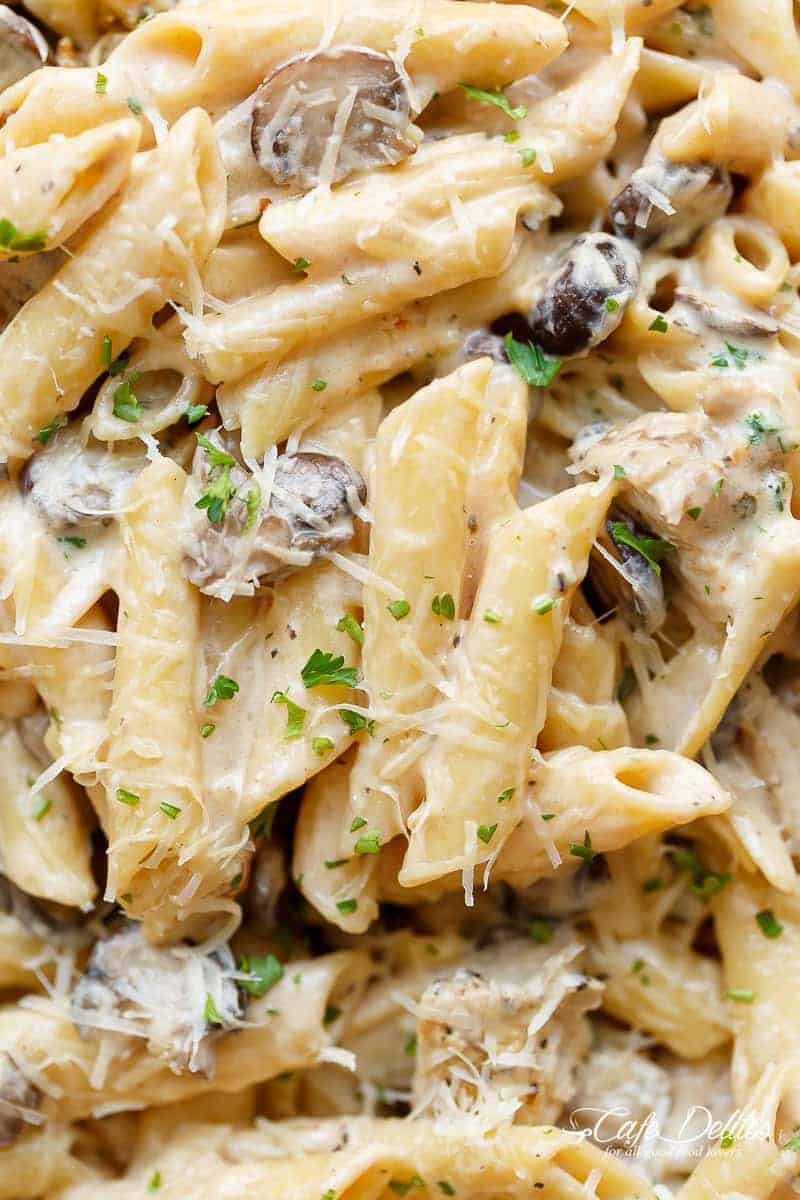 Close up image of seared meat strips mixed through the dish with  garlic, mushrooms and parmesan cheese with fresh herbs sprinkled on top. 