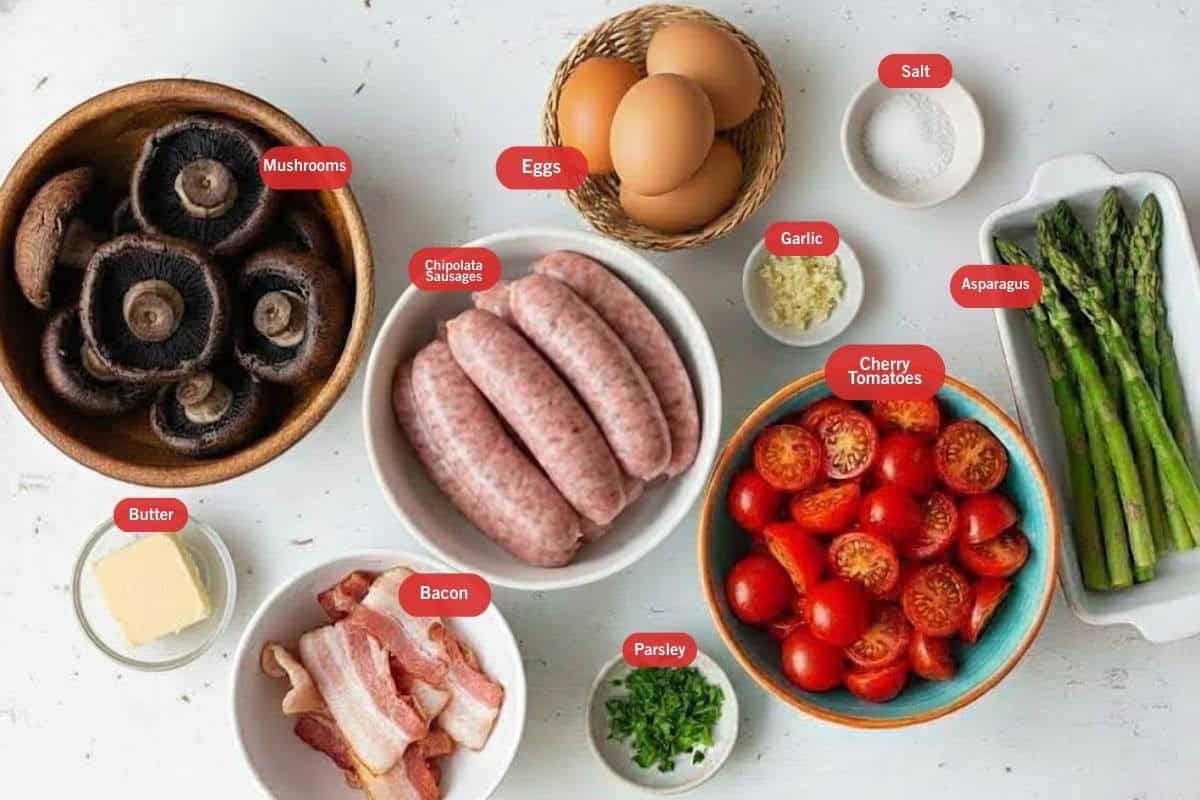 Flat lay photo of ingredient shot of mushrooms, eggs, salt, asparagus, cherry tomatoes, chipotala sausage, butter, bacon parsley