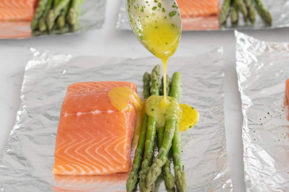 Adding lemon butter mixture over the salmon and asparagus.
