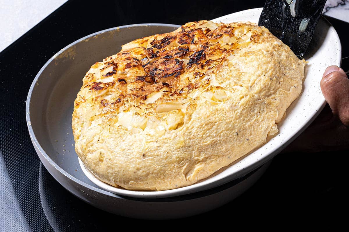 fried spanish omelette being flipped close up in the pan
