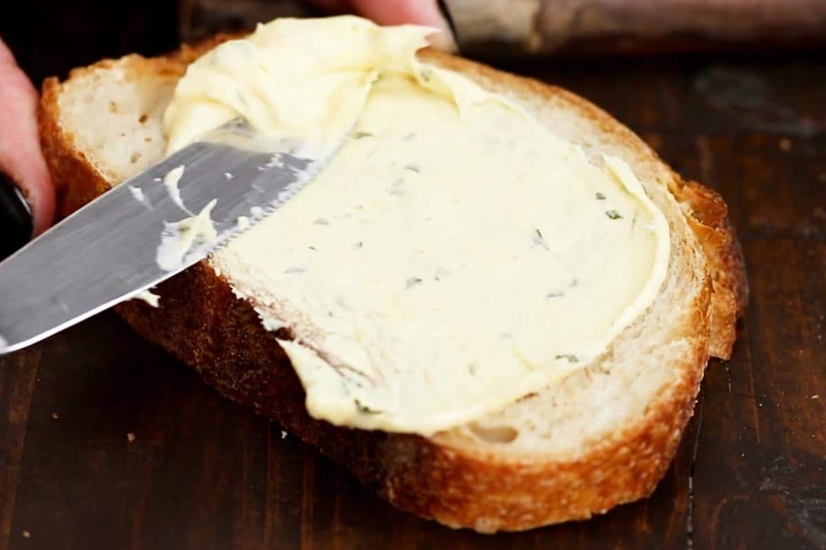 Spreading garlic butter on the bread.