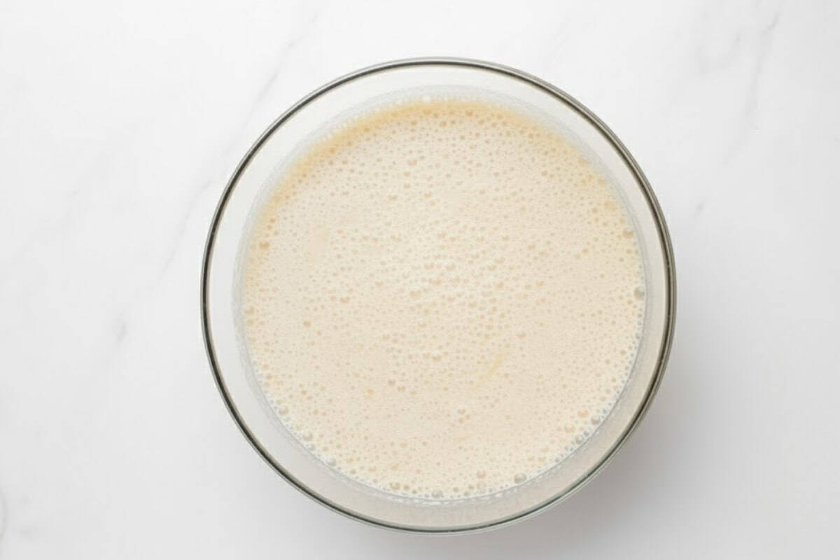 In a large bowl, combine warm milk, yeast, 2 tablespoons of sugar, and melted butter.